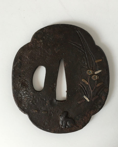 Antique Japanese Edo-period iron tsuba with silver inlay depicting a seated dog beneath chrysanthemum flowers, approximately 7.4 cm in diameter.