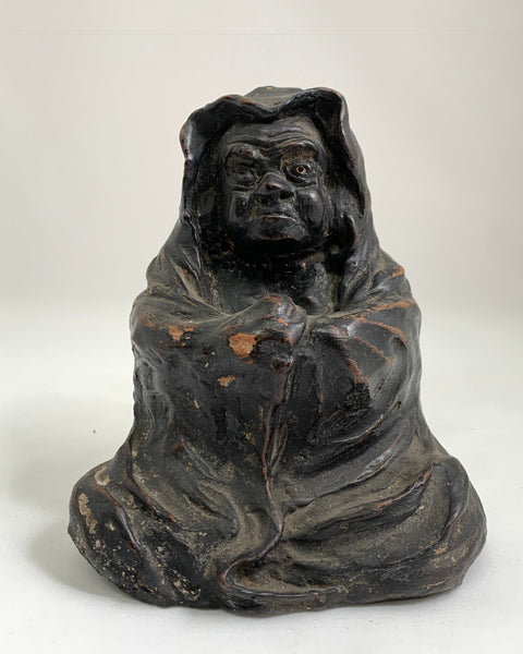 Antique Japanese hand-formed clay Daruma figure with aged black surface, hooded robe, and expressive carved face.