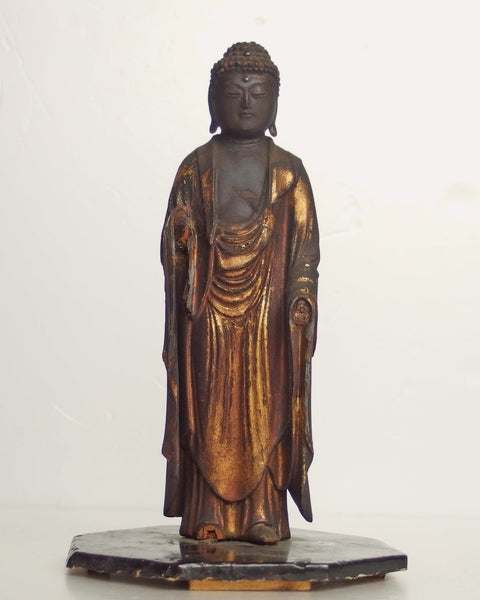 Antique Japanese carved wood standing Amida Buddha sculpture with aged gilt finish displayed on a wooden base.