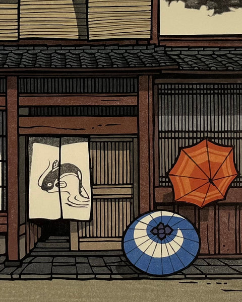 Traditional Japanese scene with colorful umbrellas in front of a wooden building.