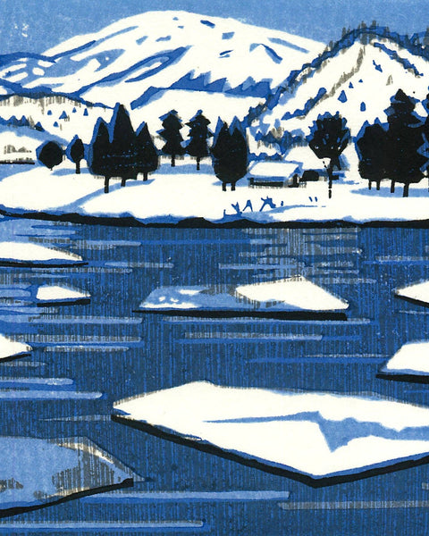 Winter landscape with snow-covered mountains, trees, and a lake.