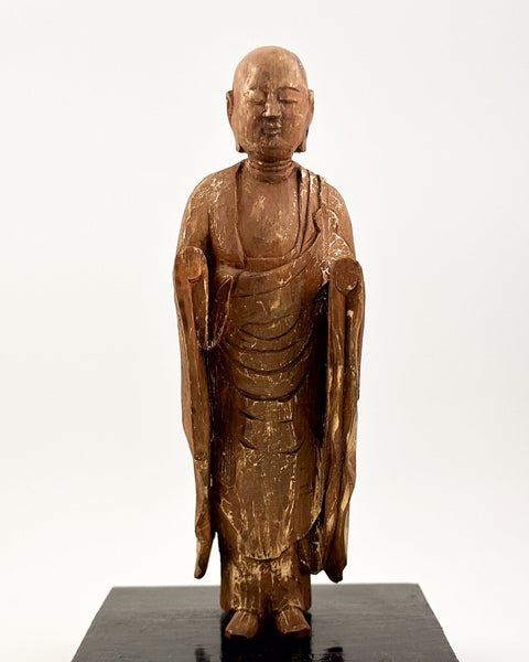 Vintage carved wooden Jizō sculpture with traces of gilt standing on a later black wooden base.